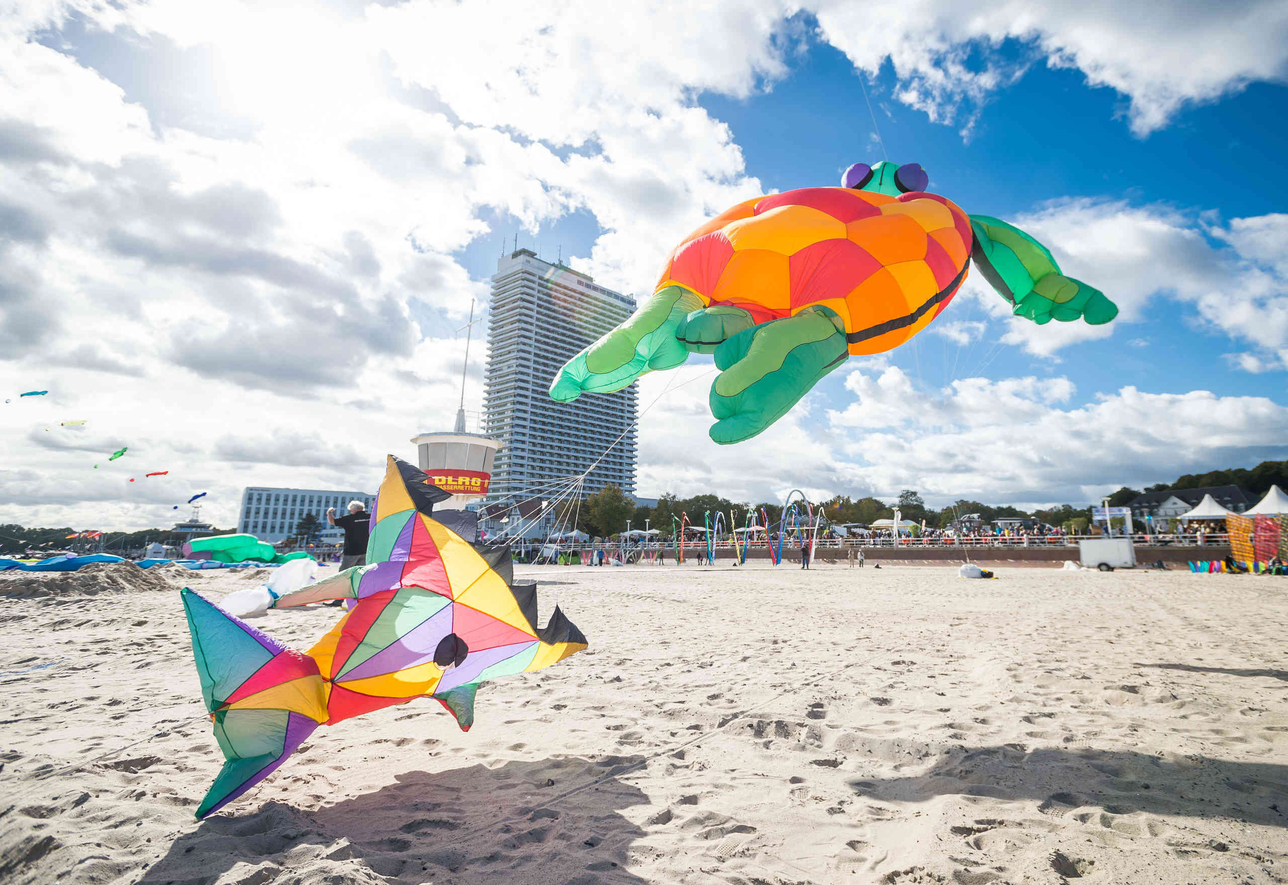 Personen lassen am Travemünder Strand Drachen steigen