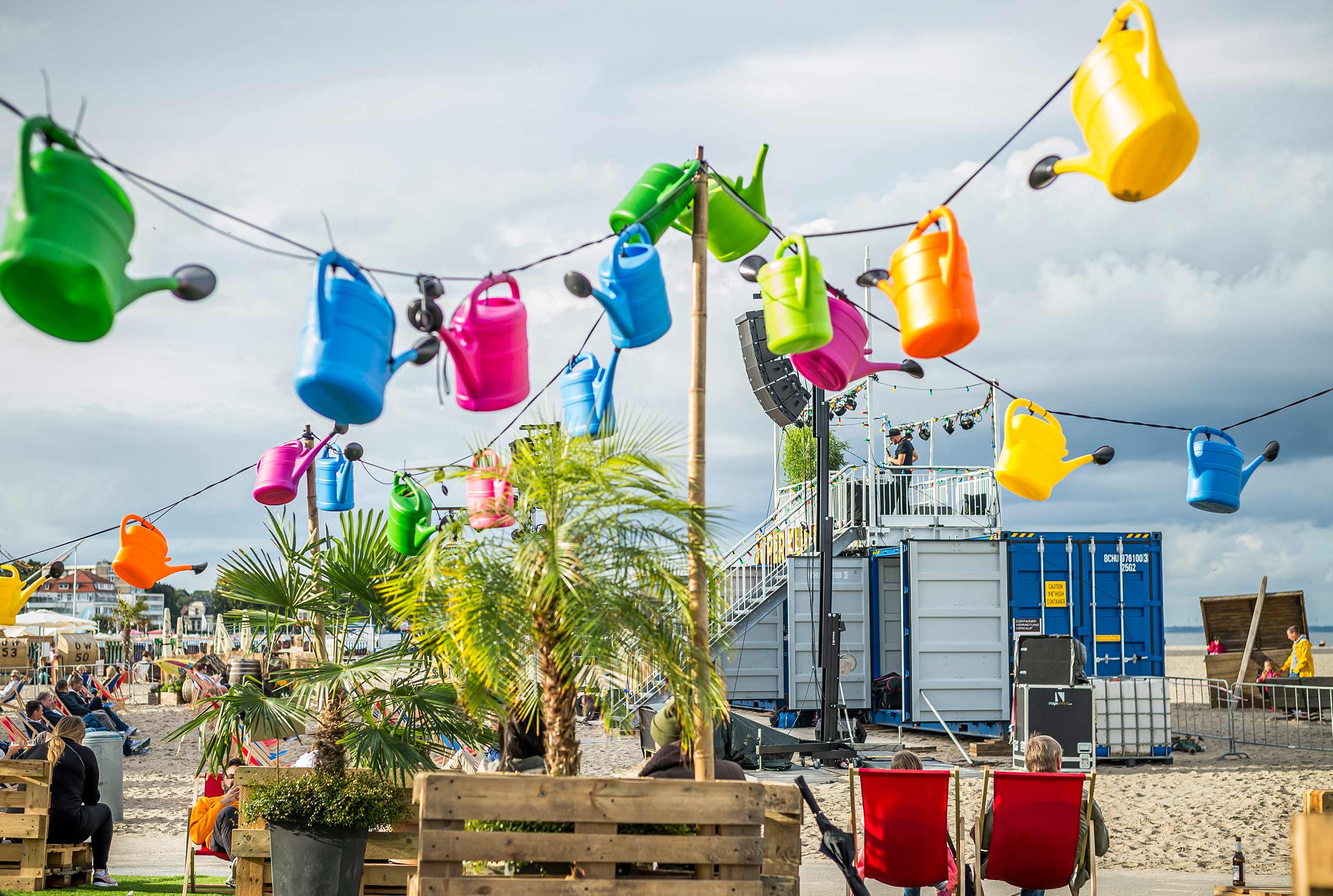 Bunte Gießkannen und Liegestühle auf dem Weite Welt Festival am Travemünder Strand